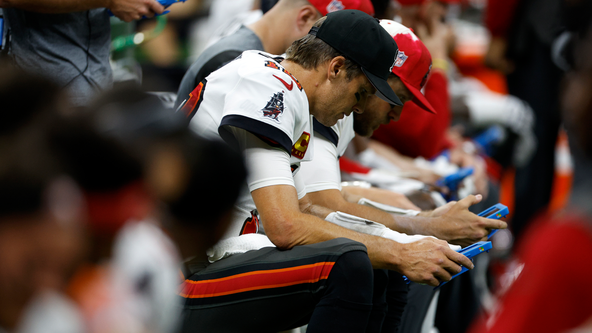 Tom Brady look at a tablet on the sideline