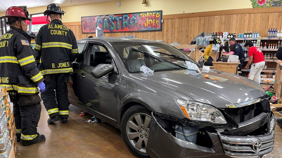 Firefighters near damaged car inside grocery store