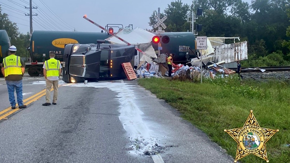 overturned semi-truck and train at rail crossing