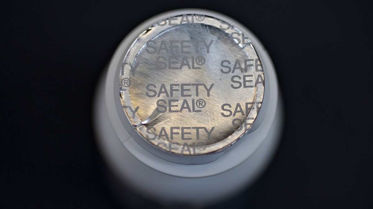 The top of an opened bottle showing a silver safety seal.