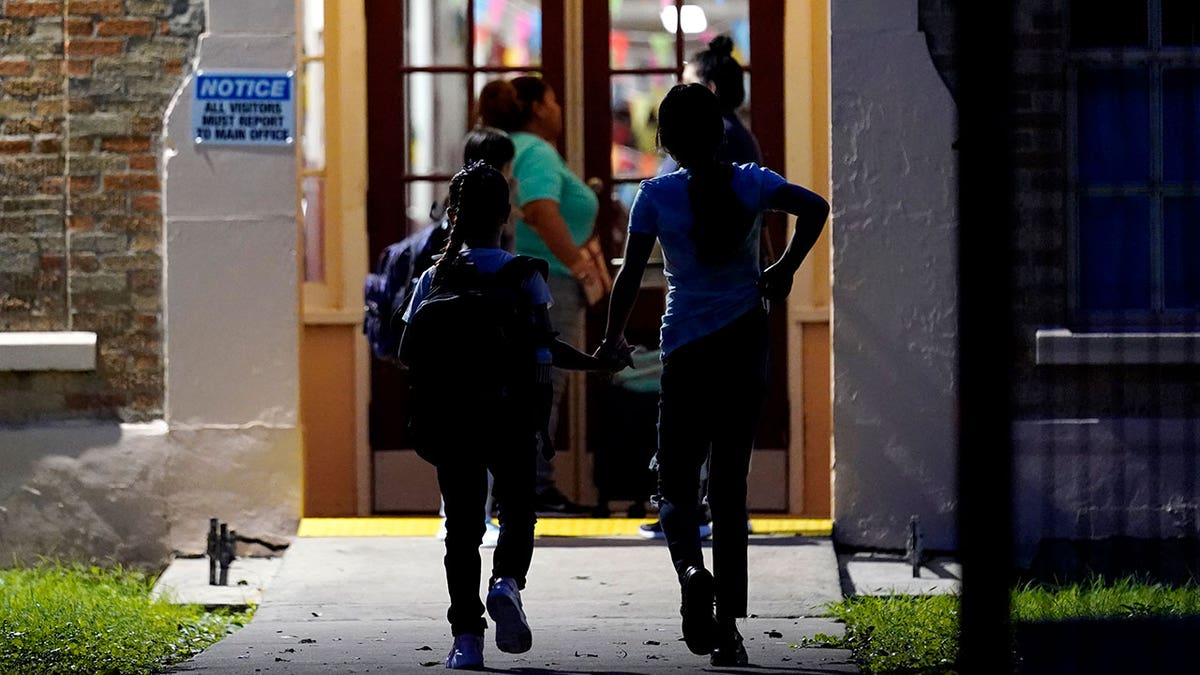 Two Uvalde students hold hands as they walk through a hallway