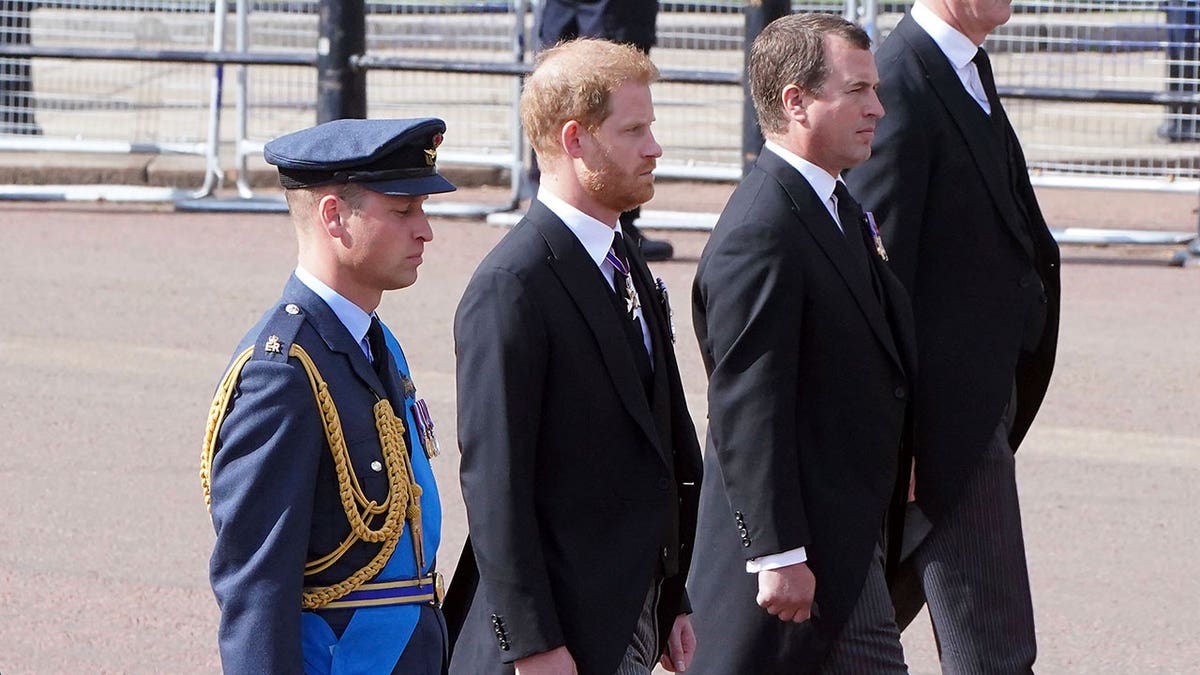 William, dressed in military uniform, and Harry, dressed in a suit, walk during Queen's procession