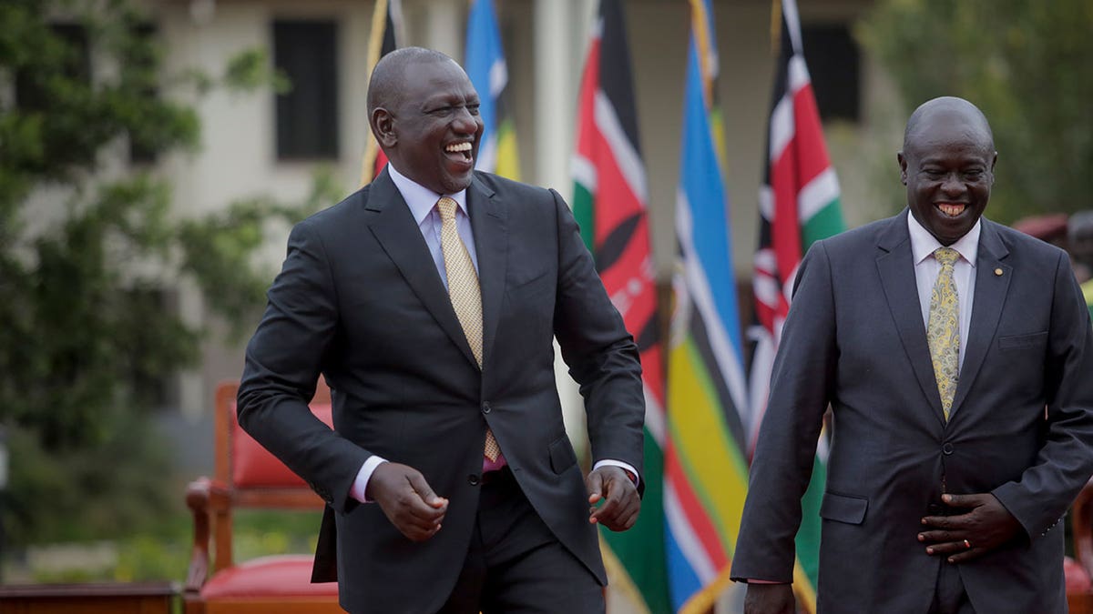 William Ruto, on left, laughs while wearing a dark suit and yellow tie while Rigathi Gachagua, right, also laughs while wearing a dark suit