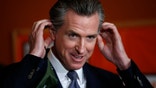 Democratic California Gov. Gavin Newsom removes his mask before a press conference.