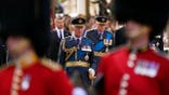 King Charles is dressed in military uniform as he follows behidn guards and the Queen's coffin
