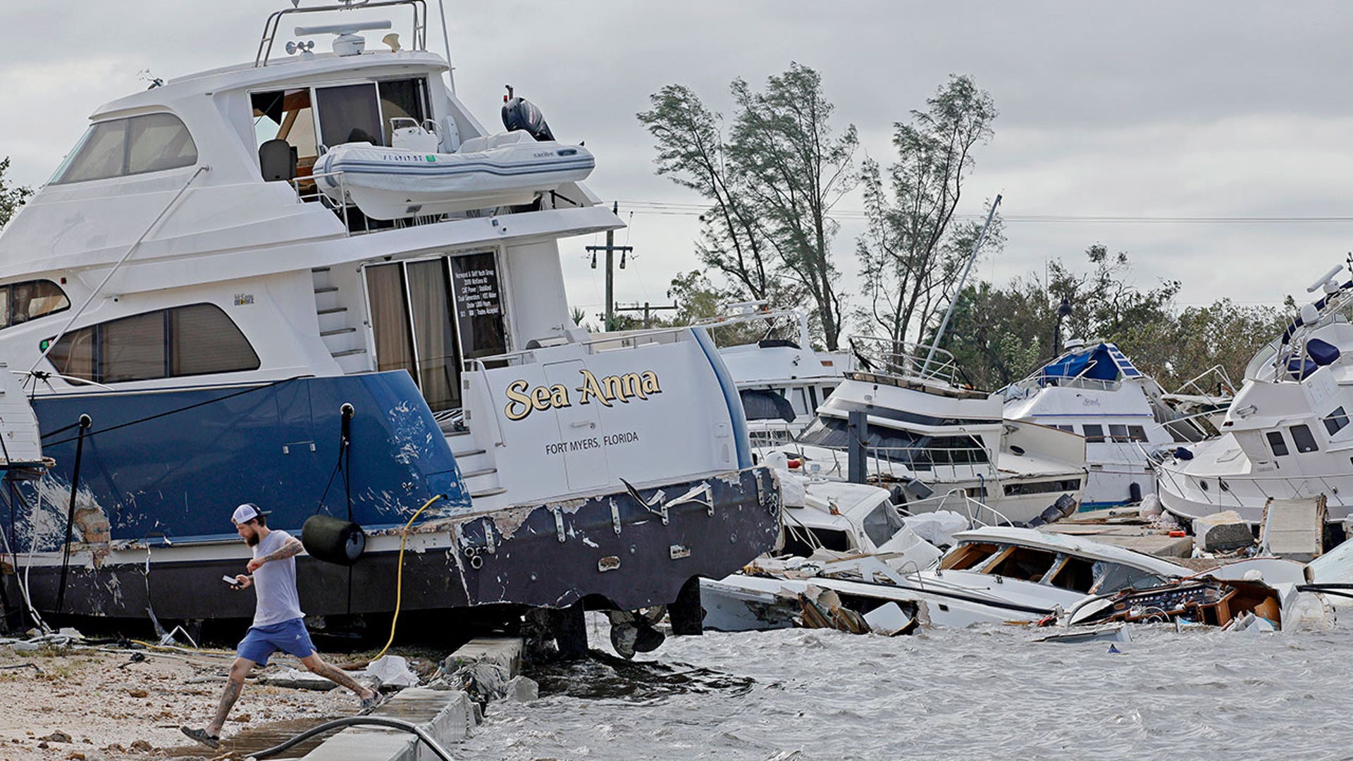 A man runs beside a battered boat in Fort Meyers during Hurricane Ian