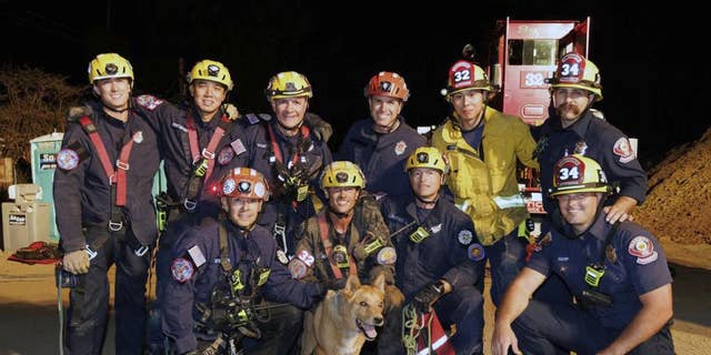 This image, provided by the Pasadena Fire Department, shows firefighters posing with Cesar, a blind dog that was rescued from a hold in Pasadena, Calif., on Tuesday, Sept. 20, 2022.