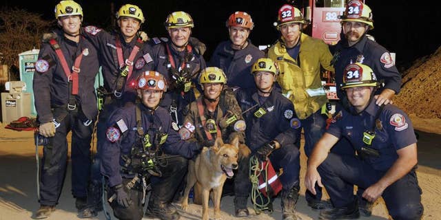 This image, provided by the Pasadena Fire Department, shows firefighters posing with Cesar, a blind dog that was rescued from a hold in Pasadena, Calif., on Tuesday, Sept. 20, 2022.