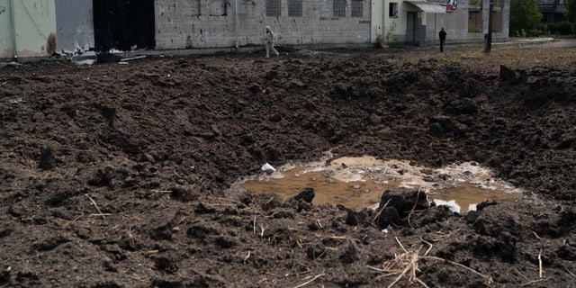People pass the crater of an explosion that hit an area near the Ukrainian Red Cross Society during a Russian attack yesterday in Sloviansk, Ukraine on Monday, September 5, 2022.