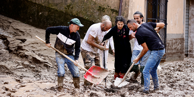 People help an elderly woman after heavy rains and deadly floods hit the central Italian region of Marche, in Cantiano, Italy, Sept. 16, 2022.