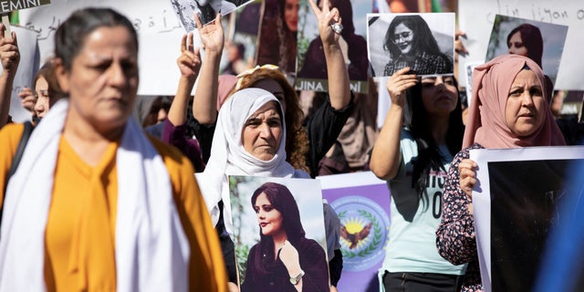 Women carry pictures during a protest over the death of 22-year-old Kurdish woman Mahsa Amini in Iran, in the Kurdish-controlled city of Qamishli, northeastern Syria Sept. 26, 2022.  