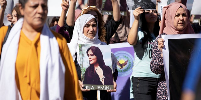 Women carry pictures during a protest over the death of 22-year-old Kurdish woman Mahsa Amini in Iran, in the Kurdish-controlled city of Qamishli, northeastern Syria Sept. 26, 2022.