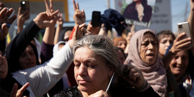 A woman cuts her hair during a protest against the death of 22-year-old Kurdish woman Masa Amini in the Kurdish-controlled city of Qamishri in northeastern Syria on September 26, 2022.  