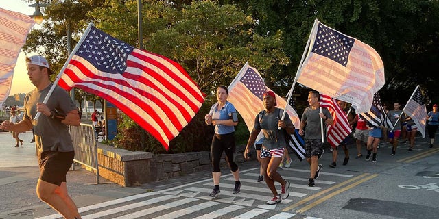 9/11 Promise Run participants are shown participating with American flags at the end of the race on Sept. 11, 2021.
