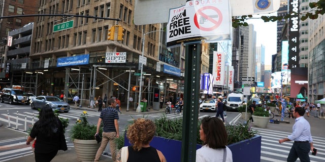  People walk past a "Gun Free Zone" sign posted on 40th Street and Broadway on August 31, 2022 in New York City.