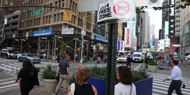  People walk past a "Gun Free Zone" sign posted on 40th Street and Broadway on August 31, 2022 in New York City.