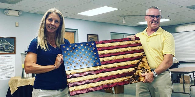 9/11 Promise founder and president Jen Depoto (left) holds a wood-carved American flag at Vienna Volunteer Fire Department on Sept. 8, 2022.