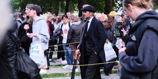 David Beckham wore a cap and a dark jacket while waiting in queue.