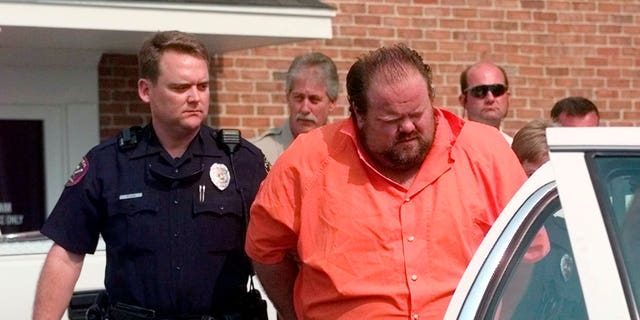 Officials escort murder suspect Alan Eugene Miller away from the Pelham City Jail in Alabama in 1999. Miller, scheduled to be put to death by lethal injection on Sept. 22, 2022, for a workplace shooting rampage in 1999 that killed three men, says the state lost the paperwork he turned in selecting an alternate execution method.