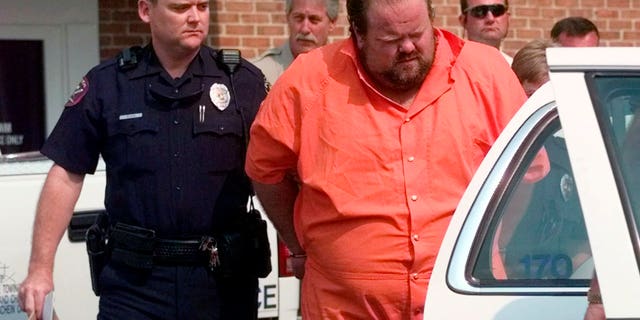 Officials escort murder suspect Alan Eugene Miller away from the Pelham City Jail in Alabama in 1999. Miller, scheduled to be put to death by lethal injection on Sept. 22, 2022, for a workplace shooting rampage in 1999 that killed three men, says the state lost the paperwork he turned in selecting an alternate execution method.