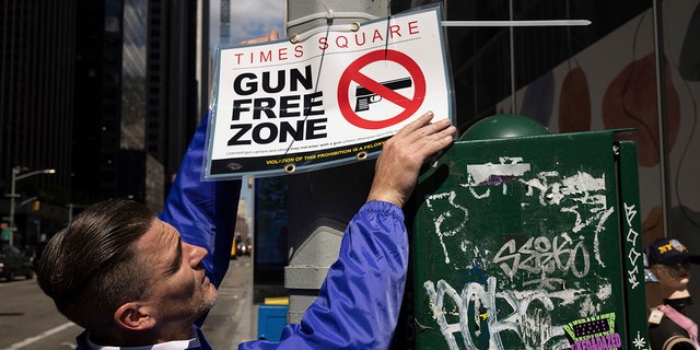 A New York Police Department Public Affairs officer sets up signs reading Gun Free Zone around Times Square, Wednesday, Aug. 31, 2022, in New York. 