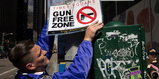 An New York Police Department Public Affairs officer sets up signs reading Gun Free Zone around Times Square, Wednesday, Aug. 31, 2022, in New York. 