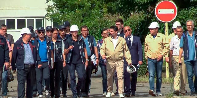 In this handout photo taken from video released by Russian Defense Ministry Press Service on Friday Sept. 2, 2022, International Atomic Energy Agency (IAEA) director Rafael Grossi, the mission leader, center in white helmet, and IAEA members walk while inspecting the Zaporizhzhia Nuclear Power Plant