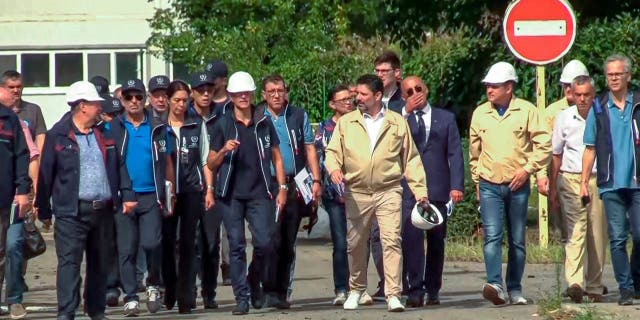 In this handout photo taken from video released by Russian Defense Ministry Press Service on Friday Sept. 2, 2022, International Atomic Energy Agency (IAEA) director Rafael Grossi, the mission leader, center in white helmet, and IAEA members walk while inspecting the Zaporizhzhia Nuclear Power Plant
