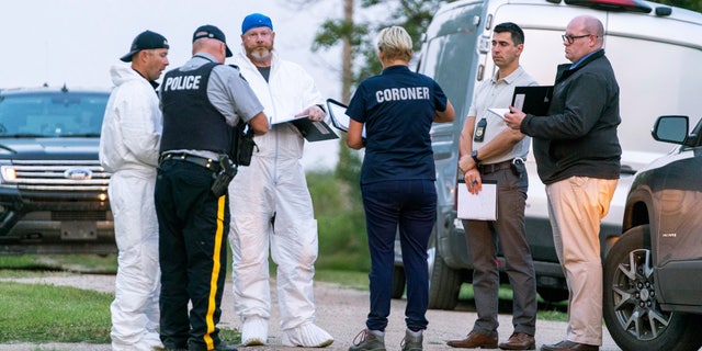 Investigators gather in front of the scene of a stabbing in Weldon, Saskatchewan, Sunday, Sept. 4, 2022. A series of stabbings at an Indigenous community and at another in the village of Weldon left multiple people dead and others wounded.