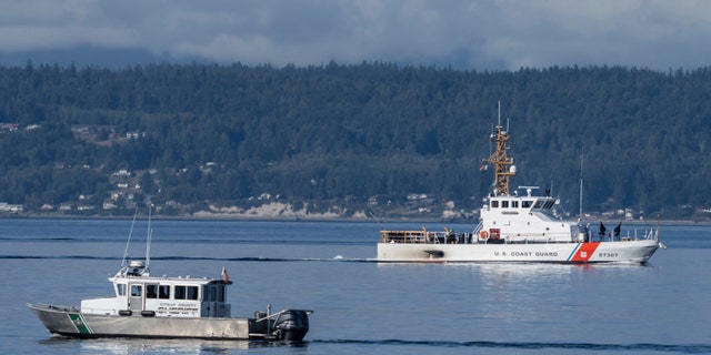 A U.S. Coast Guard boat and Kitsap, Wash., County Sherrif boat search the area, Monday, Sept. 5, 2022, near Freeland, Wash., on Whidbey Island north of Seattle where a chartered floatplane crashed the day before.