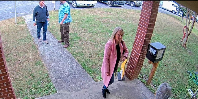 In this image taken from Coffee County, Georgia, security video, Cathy Latham, bottom, who was the chair of the Coffee County Republican Party at the time, greets a team of computer experts from data solutions company SullivanStrickler at the county election office in Douglas, Georgia.
