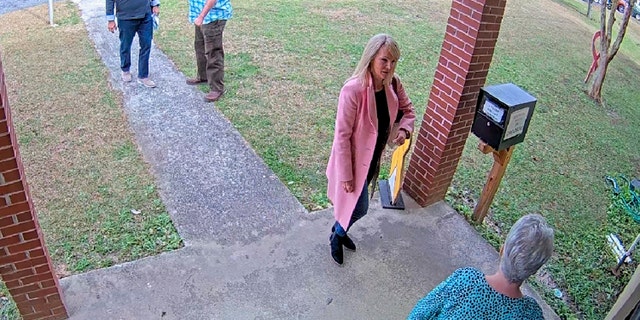 In this image taken from Coffee County, Georgia, security video, Cathy Latham, bottom, who was the chair of the Coffee County Republican Party at the time, greets a team of computer experts from data solutions company SullivanStrickler at the county election office in Douglas, Georgia.