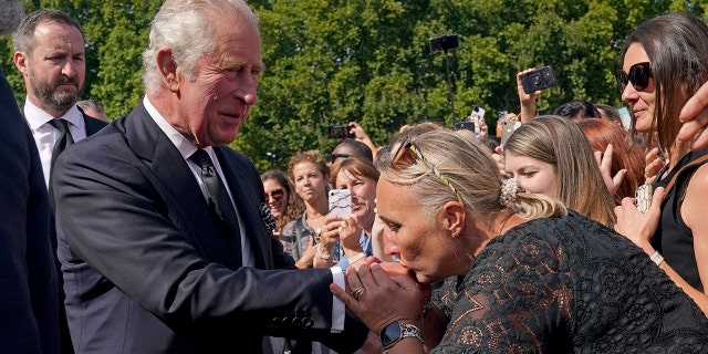 A well-wisher kisses the hand of Britain's King Charles III.