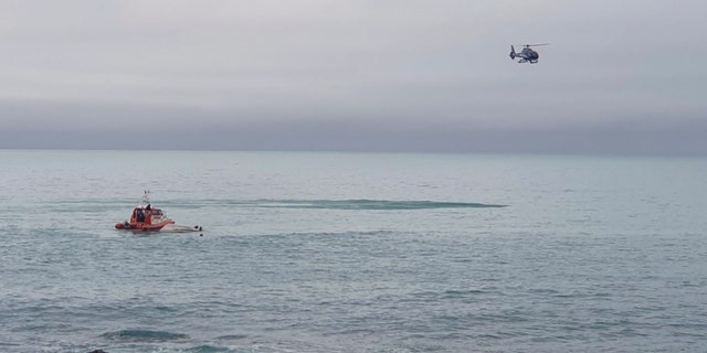 A helicopter and a rescue boat search for survivors off the coast of Kaikoura, New Zealand, Saturday, Sept. 10, 2022. 