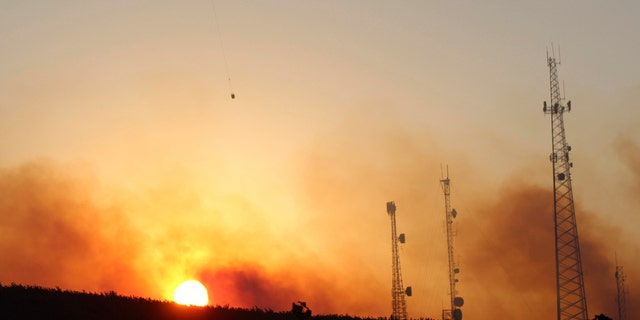 A helicopter carries water on a longline to a wildfire near Salem, Ore., at sunset Friday, Sept. 9, 2022. Climate change is bringing drier conditions to the Pacific Northwest and that requires strategies that have been common in fire-prone California for the past decade or more, said Erica Fleishman, director of the Oregon Climate Change Research Institute at Oregon State University. 