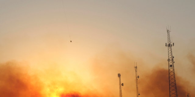 A helicopter carries water on a longline to a wildfire near Salem, Ore., at sunset Friday, Sept. 9, 2022. Climate change is bringing drier conditions to the Pacific Northwest and that requires strategies that have been common in fire-prone California for the past decade or more, said Erica Fleishman, director of the Oregon Climate Change Research Institute at Oregon State University. 