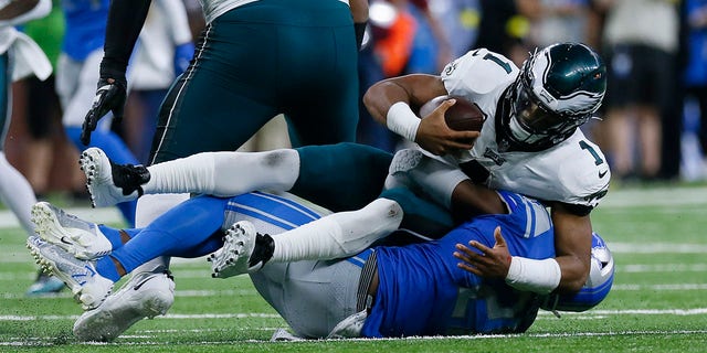 Detroit Lions safety Tracy Walker III (21) tackles Philadelphia Eagles quarterback Jalen Hurts (1) in the first half of an NFL football game in Detroit, Sunday, Sept. 11, 2022. 