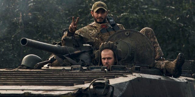 A Ukrainian soldier shows a V-sign atop a vehicle in Izium, Kharkiv region, Ukraine, Tuesday, Sept. 13, 2022. 