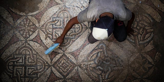 Un palestinian mătură praful părți dintr-o podea de mozaic din epoca bizantină care a fost descoperită de un fermier în Bureij, în centrul Fâșiei Gaza, pe 5 septembrie 2022. 