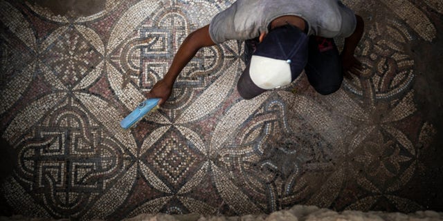 A Palestinian sweeps dust off parts of a Byzantine-era mosaic floor that was uncovered by a farmer in Bureij in central Gaza Strip, Sept. 5, 2022.