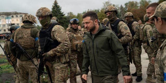 Surrounded by soldiers the Ukrainian President Volodymyr Zelenskyy attends a national flag-raising ceremony in the freed Izium, Ukraine, Wednesday, Sept. 14, 2022.