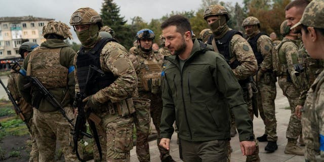 Surrounded by soldiers the Ukrainian President Volodymyr Zelenskyy attends a national flag-raising ceremony in the freed Izium, Ukraine, Wednesday, Sept. 14, 2022. Zelenskyy visited the recently liberated city on Wednesday, greeting soldiers and thanking them for their efforts in retaking the area, as the Ukrainian flag was raised in front of the burned-out city hall building.