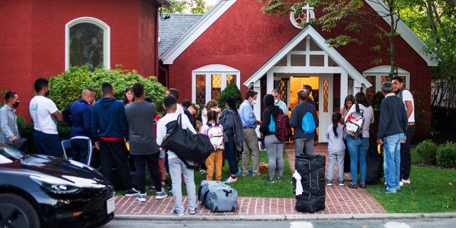 Immigrants gather with their belongings outside St. Andrews Episcopal Church, Wednesday Sept. 14, 2022, in Edgartown, Mass., on Martha's Vineyard.