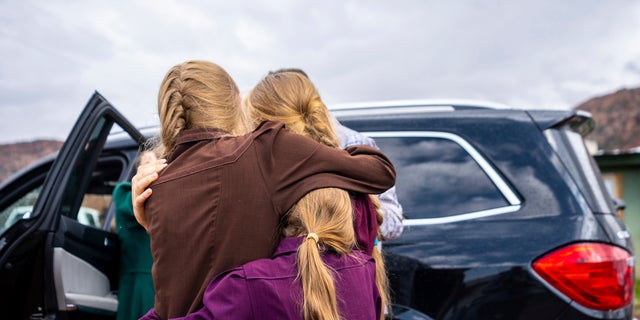 Three girls embrace before they are removed from the home of Samuel Bateman, following his arrest in Colorado City, Arizona, on Sept. 14, 2022. Seven were removed from the Bateman home, as well as two others from another house as part of the investigation. 