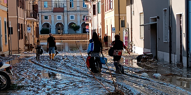 People walk on mud and debris in Senigallia, Italy on Friday, September 16, 2022.