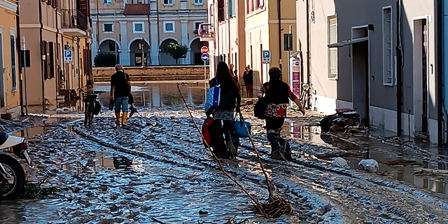 People walk on mud and debris in Senigallia, Italy, Friday Sept. 16, 2022.
