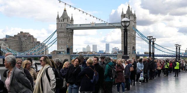 People wait in a queue in front of Tower Bridge to pay their respect to the late Queen Elizabeth II as her coffin lies in state in Westminster Hall, London, Friday, Sept. 16, 2022.