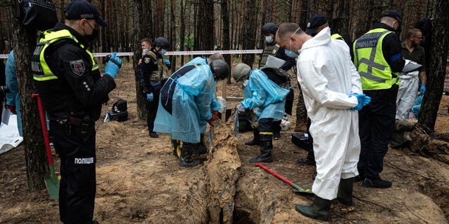 Emergency workers move a body during an exhumation in the recently taken area of ​​Izium, Ukraine, Friday, Sept.  16, 2022.