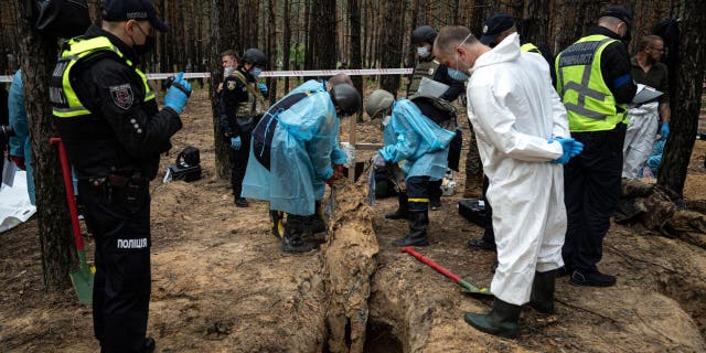 Emergency workers move a body during an exhumation in the recently taken area of ​​Izium, Ukraine, Friday, Sept.  16, 2022.