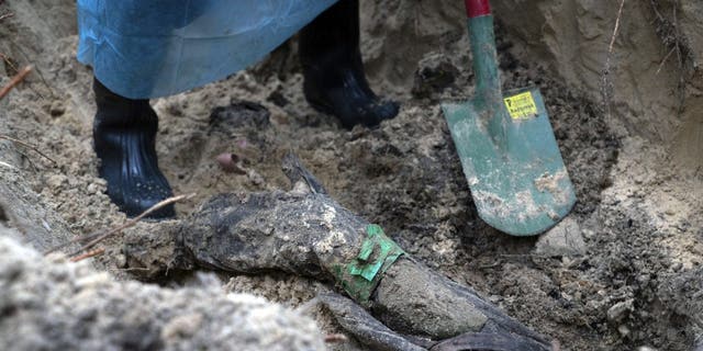 Part of the body of Ukrainian soldier emerges from the ground during an exhumation in the recently retaken area of Izyum, Ukraine, Friday, Sept. 16, 2022. 